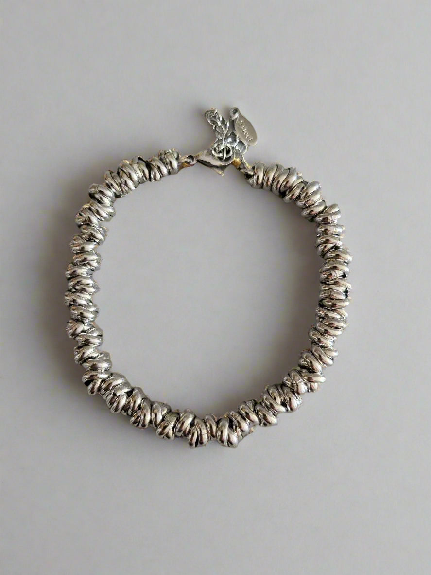 A silver-colored linked bracelet with a jewelry clasp on a plain background.