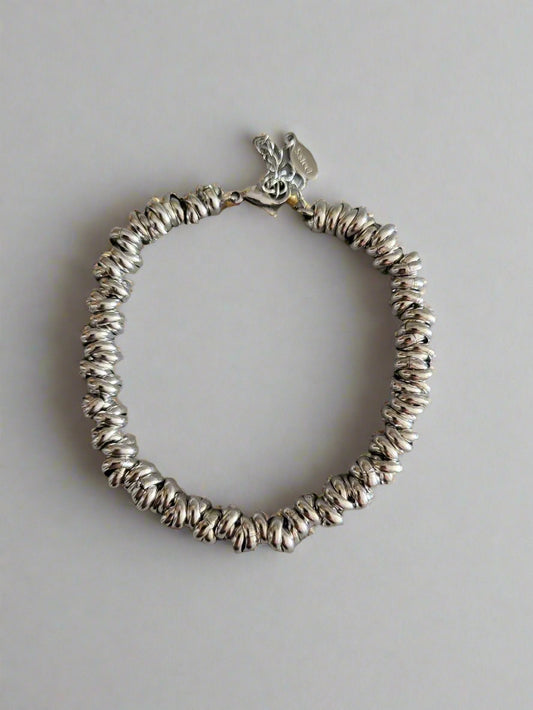 A silver-colored linked bracelet with a jewelry clasp on a plain background.