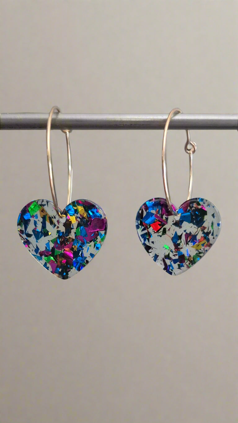 Heart-shaped earrings with multicolor speckles on a gray background
