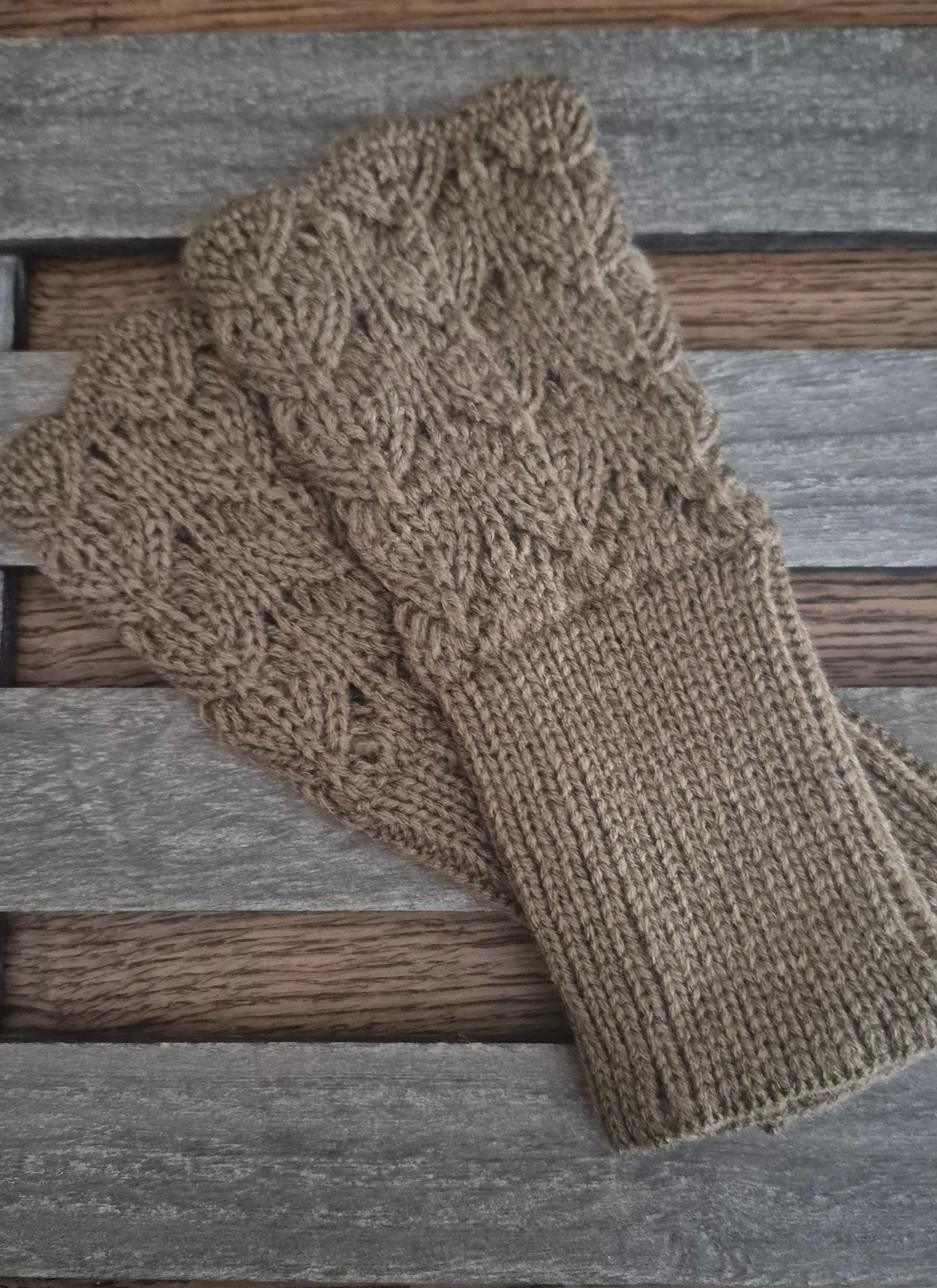 Pair of brown knitted gloves on a wooden surface