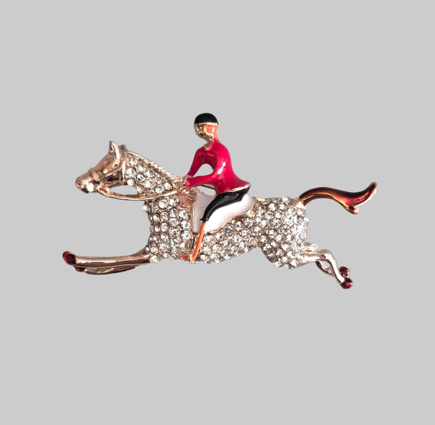 Brooch of a horse and jockey on a gray background