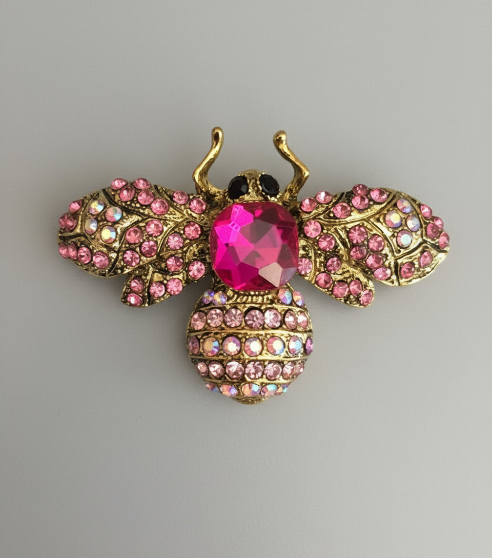 Decorative bee brooch with pink gemstones on a gray background
