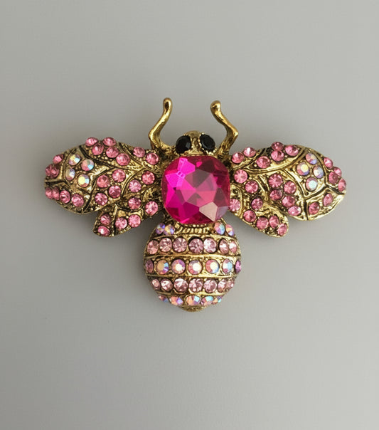 Decorative bee brooch with pink gemstones on a gray background