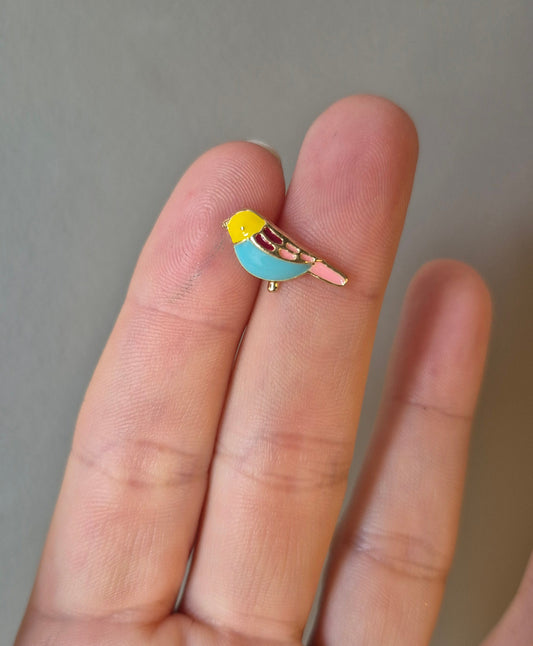 Small ring with a blue and yellow design held between fingers against a neutral background