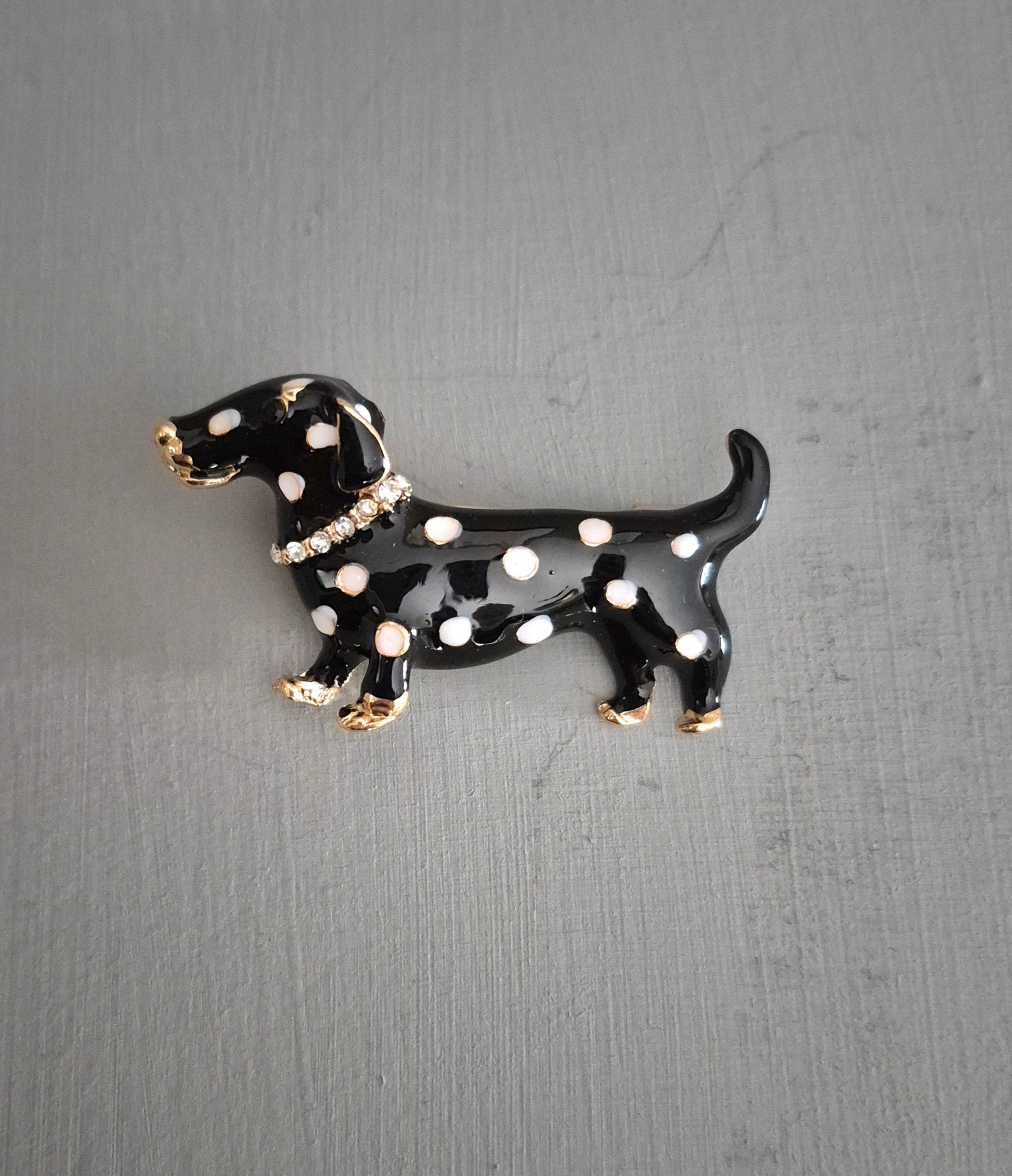 Black and white polka dot dog-shaped brooch on a gray background