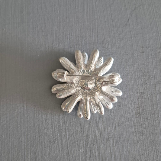 Silver flower-shaped brooch on a gray background