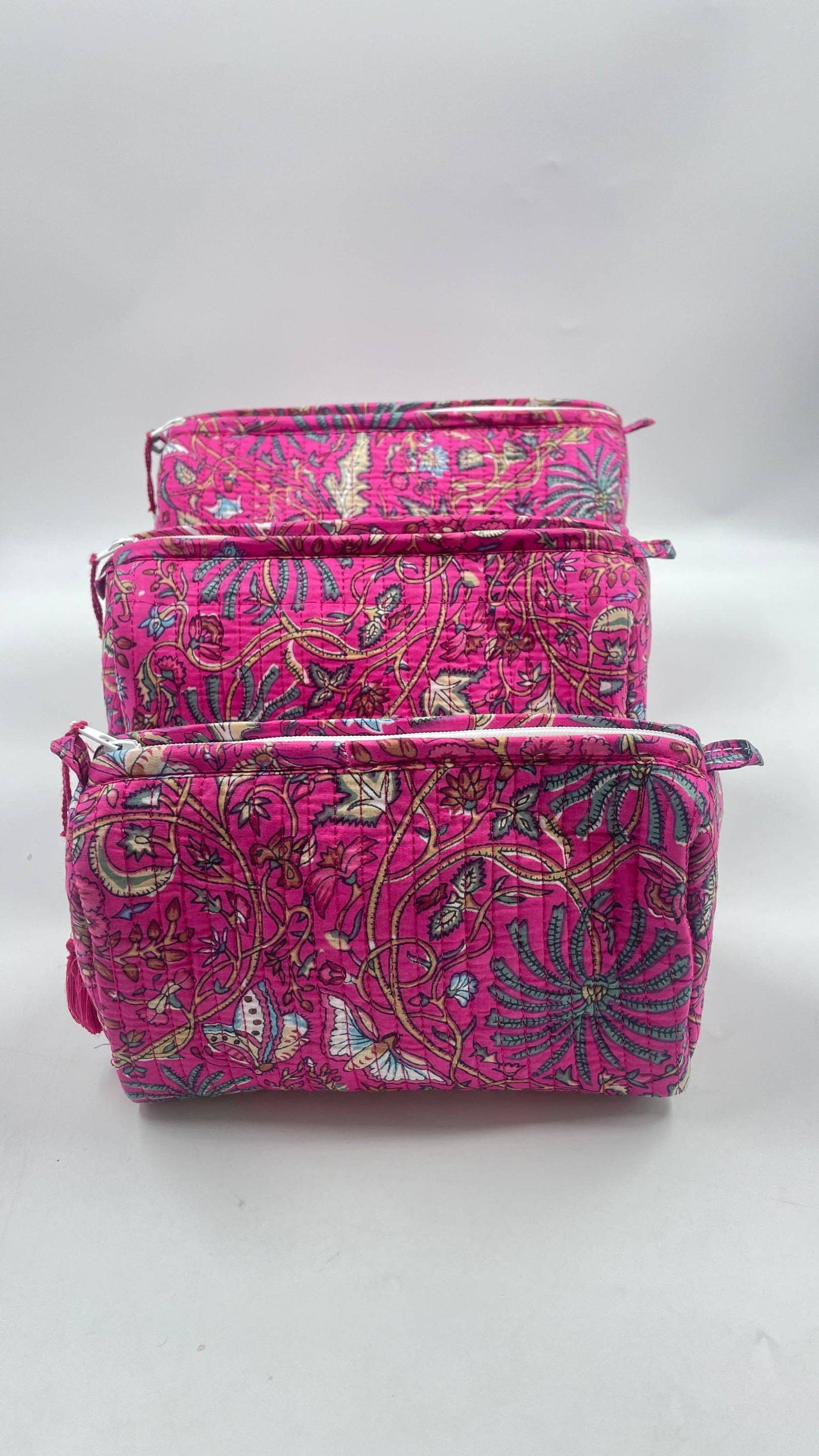Set of three pink patterned pouches on a white background
